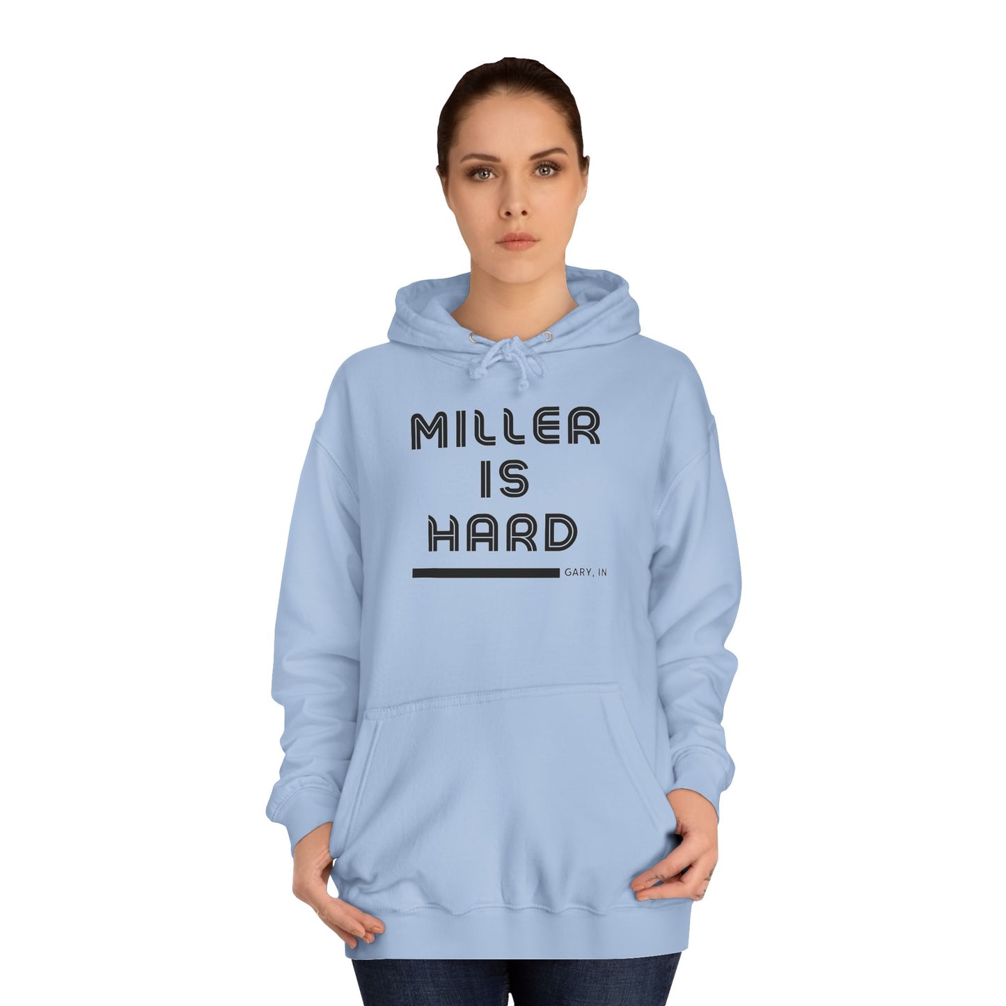 A light blue unisex college hoodie from Printify features the bold black text "MILLER IS HARD" on the front, with "GARY, IN." in smaller letters below. This hoodie is equipped with a front pocket and adjustable drawstrings, ideal for those who appreciate the Miller Beach style.