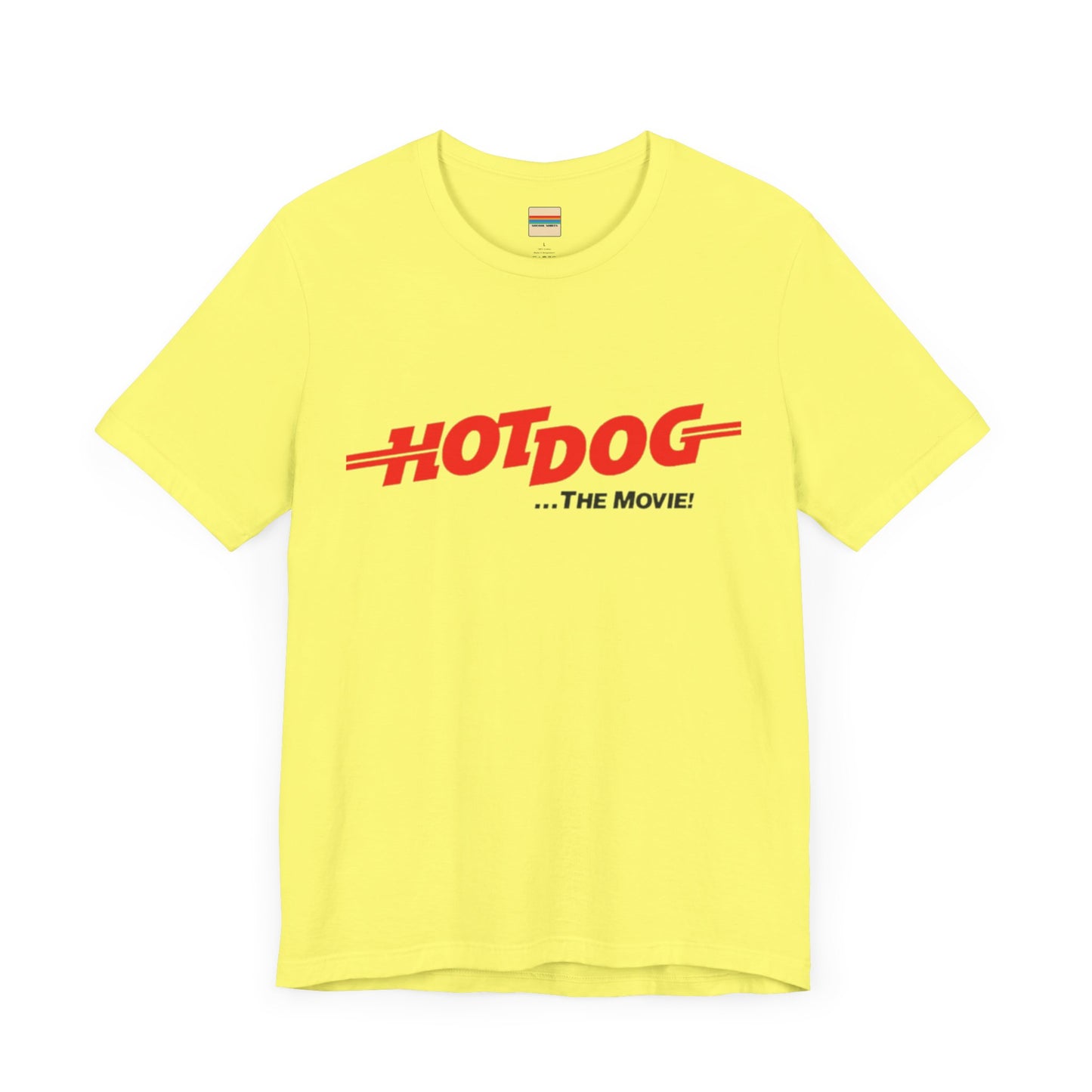 A smiling man and woman interact while wearing matching yellow "Hot Dog The Movie 1984 - Unisex Jersey Short Sleeve Tee" by Printify, featuring bold red "HOT DOG THE MOVIE" text. Their vibrant tees perfectly complement their blue jeans, with the man casually having his hands in his pockets and the woman resting one hand on his shoulder.