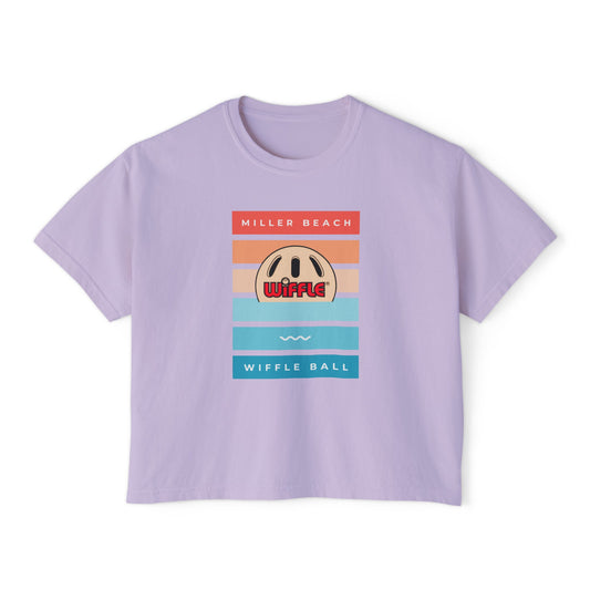 Introducing the Printify Miller Wiffle Ball Sunset Women's Boxy Tee, an oversized light purple T-shirt featuring a retro-style design with orange, beige, and light blue stripes. Made from 100% ring-spun cotton, it is adorned with a Wiffle ball graphic and the text "Miller Beach" at the top and "Wiffle Ball" at the bottom.