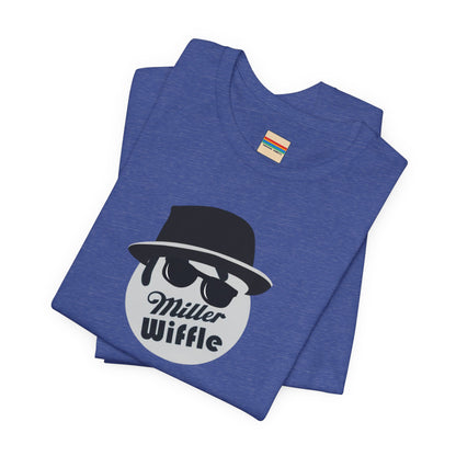 A purple unisex jersey tee from Printify, named the "Miller Wiffel Ball - Blues Brothers - Unisex Jersey Short Sleeve Tee," features a stylized graphic of a ball wearing a black fedora and sunglasses with the text "Miller Wiffel" below it. Another identical soft cotton t-shirt is neatly folded underneath, highlighting its breathable fabric.