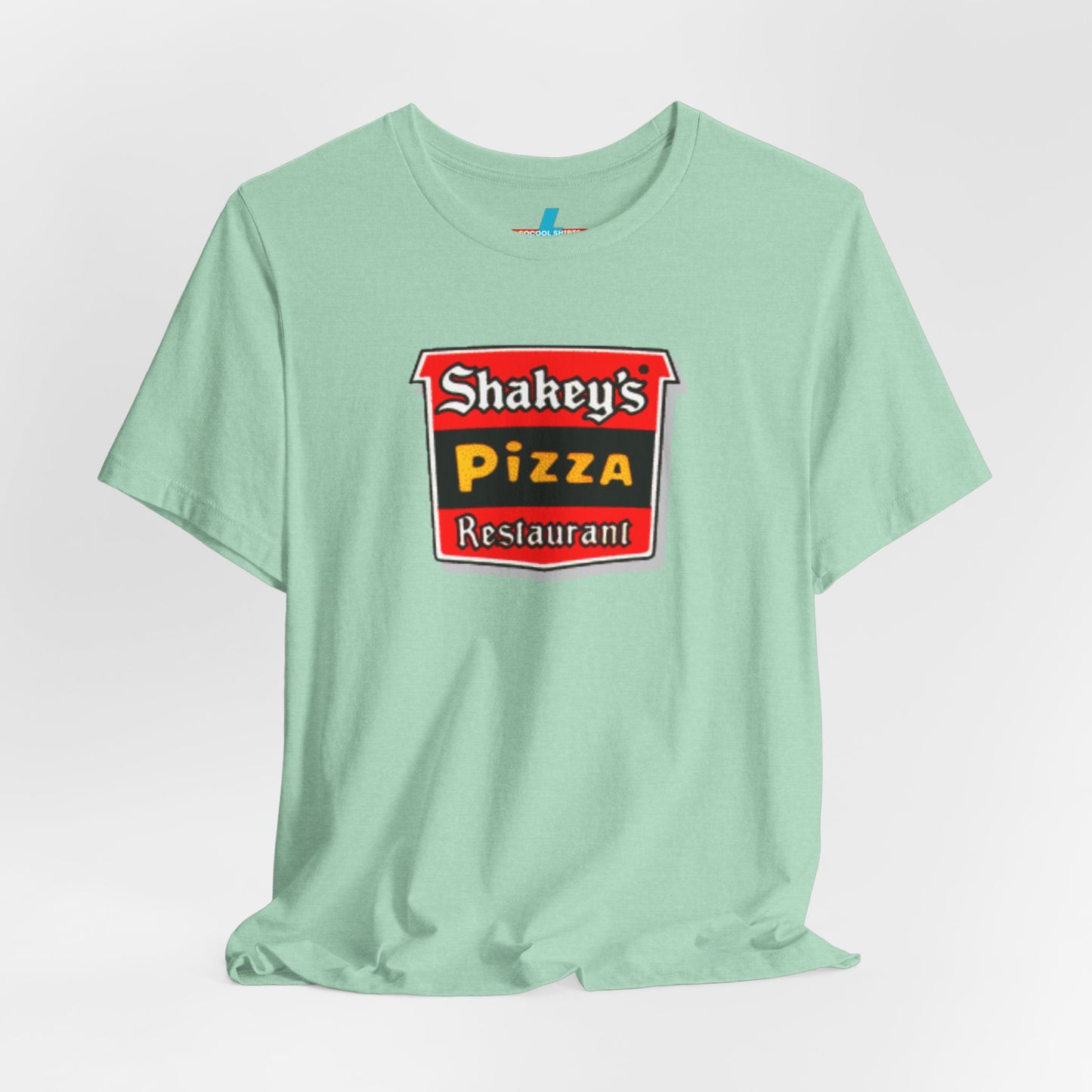 A black Shakey's Pizza - 1980s Retro Logo - Unisex T-Shirt by Printify hangs against a white background. The shirt features a colorful graphic with the text "Shakey's Pizza Restaurant" in white, yellow, and black lettering on a red background, resembling vintage pizza joints signage. This retro tee brings nostalgic vibes of classic pizzerias.