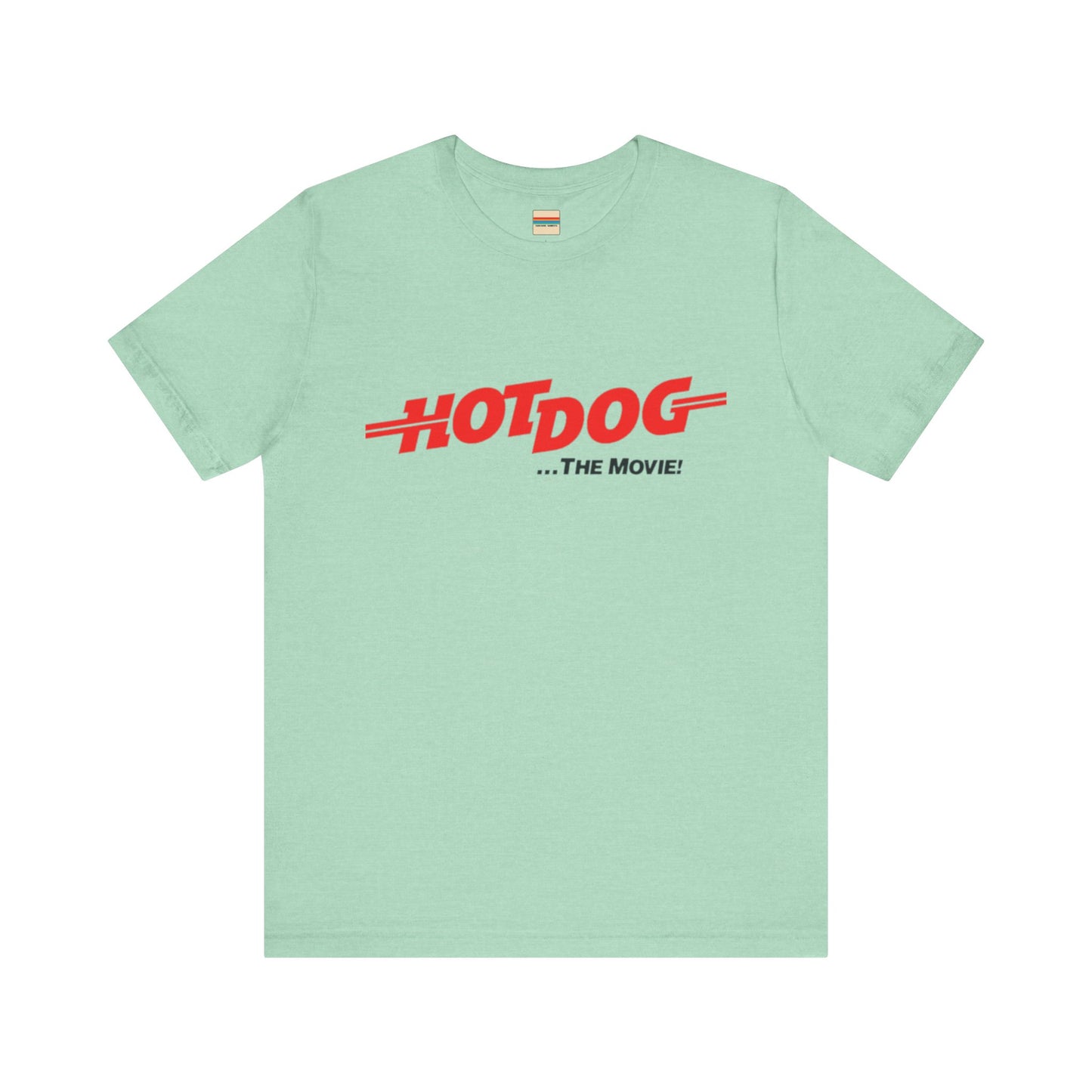 A smiling man and woman interact while wearing matching yellow "Hot Dog The Movie 1984 - Unisex Jersey Short Sleeve Tee" by Printify, featuring bold red "HOT DOG THE MOVIE" text. Their vibrant tees perfectly complement their blue jeans, with the man casually having his hands in his pockets and the woman resting one hand on his shoulder.