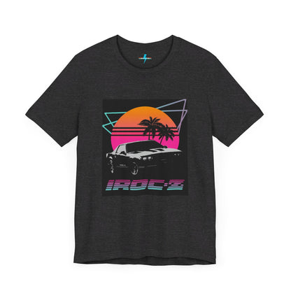 A Chevrolet Camaro iRoc Z Z28 T-Shirt 1980's by Printify, featuring a retro design with a black car, palm trees, and a sun setting in the background. The design includes geometric lines in neon colors and the text "IROC-Z" at the bottom, perfect for fans of the 1980s Chevy Camaro.