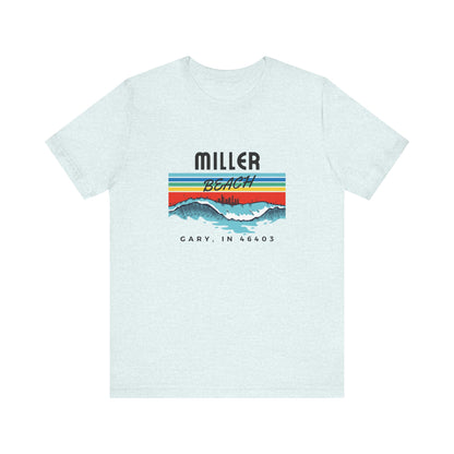 The Miller Beach 46403 Surf Style - Unisex Jersey Short Sleeve Tee by Printify features a retro surf-inspired design on a yellow background. The shirt displays "MILLER BEACH" above waves with a skyline illustration, while "Cary, IN 46403" is printed below the waves. The vibrant design also includes colorful stripes in shades of blue, red, and orange.