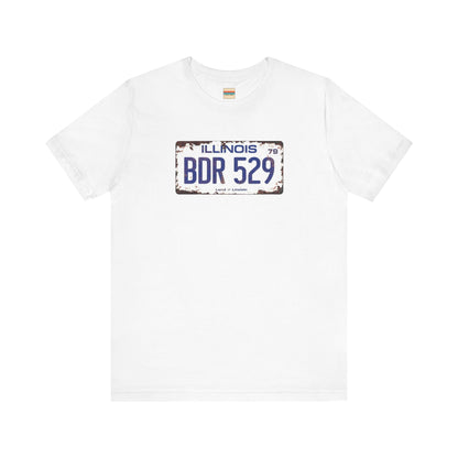 The Printify Blues Brothers BDR 529 License Plate Unisex Jersey Short Sleeve Tee showcases a vintage Illinois license plate graphic with "BDR 529" prominently displayed, as famously seen in the Blues Brothers film. The design includes "Illinois" and "Land of Lincoln" above and below the numbers, with a weathered, rustic look that enhances its retro appeal.