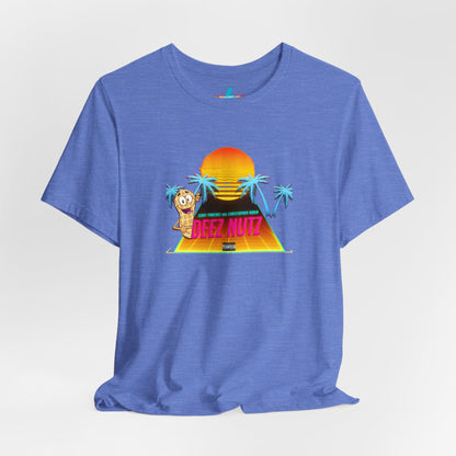 A Printify "Deez Nutz Jerry Pancake and Christopher Robin" t-shirt in purple, featuring a graphic of a sunset over a pyramid with palm trees and an illustration of an anthropomorphic nut holding a sign. The text on the shirt reads, "Just hanging out, cracking open... DEEZ NUTZ." Perfect as a unisex jersey short sleeve tee!