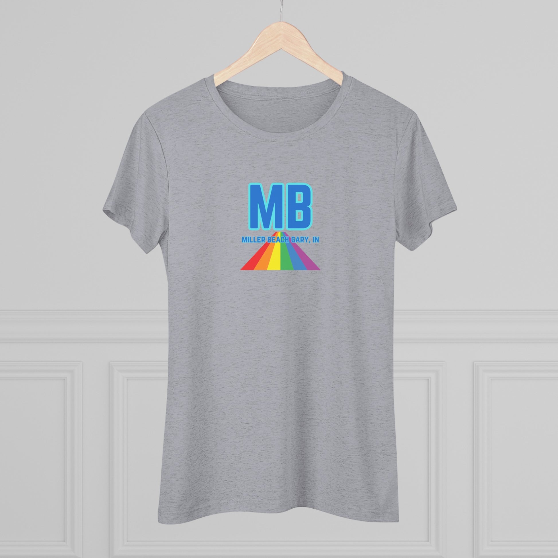 The Miller Beach Pride - Women's Triblend Tee by Printify is a dark gray, cozy t-shirt with a vintage look, featuring the text "MB" in large blue letters at the center. Below the letters, there is a rainbow-colored triangular design with "Millions & Binary, Inc." written in smaller text under the rainbow triangle.