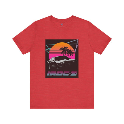 A Chevrolet Camaro iRoc Z Z28 T-Shirt 1980's by Printify, featuring a retro design with a black car, palm trees, and a sun setting in the background. The design includes geometric lines in neon colors and the text "IROC-Z" at the bottom, perfect for fans of the 1980s Chevy Camaro.