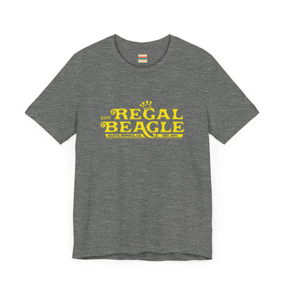 The Printify Regal Beagle - Three's Company Unisex Jersey Short Sleeve Tee, in black, showcases "The Regal Beagle, Santa Monica, CA, Est. 1977" text in a yellow vintage-style font. Crafted from 100% Airlume combed cotton for superior comfort.