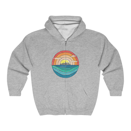 The Miller Beach Abstract - Full Zip Hooded Sweatshirt from Printify is gray and features a colorful circular graphic on the front. The graphic depicts a stylized sunset over a landscape with a blue horizon and water, transitioning to warm tones of an orange and yellow sky.