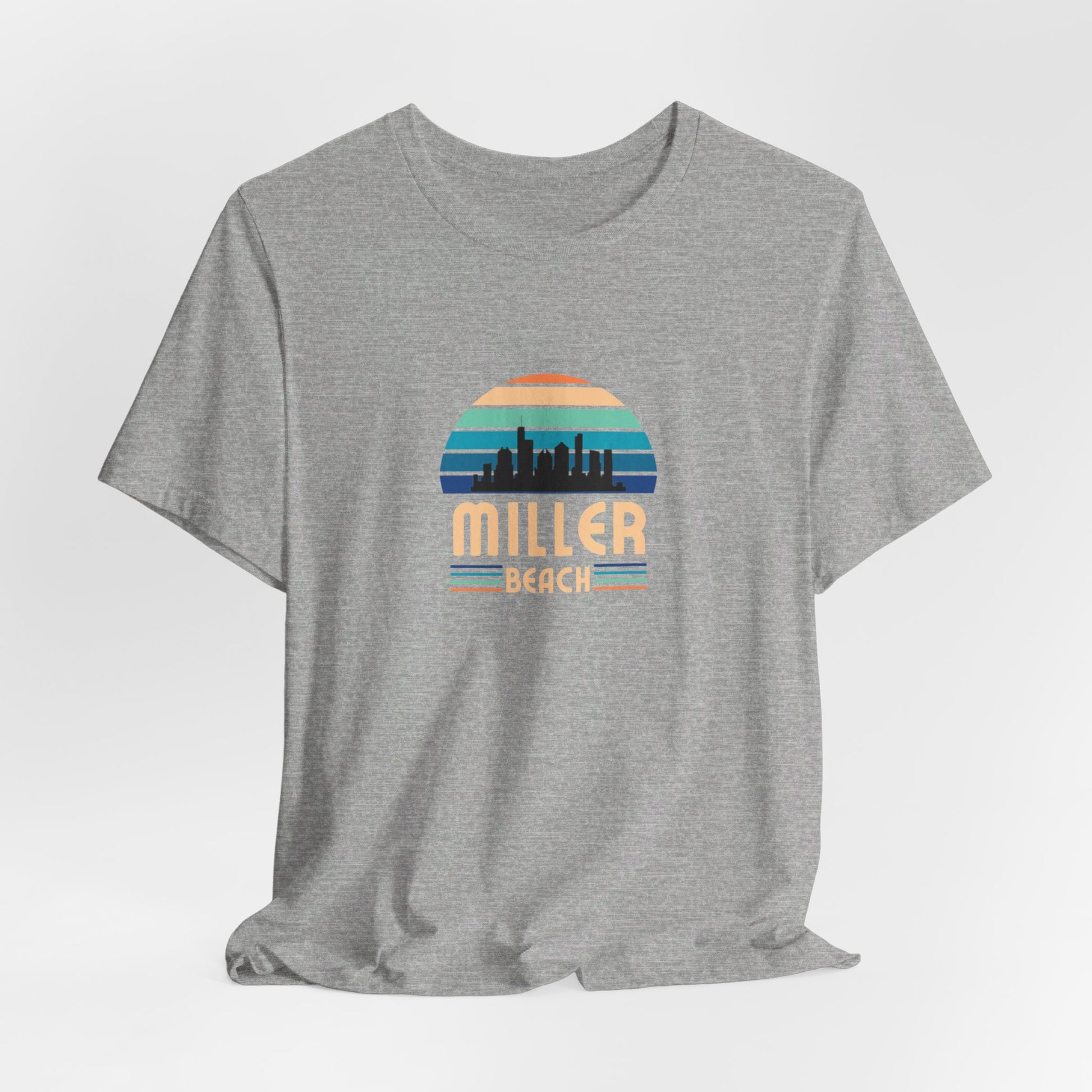 A brown unisex jersey short sleeve tee called "Miller Beach Chicago Skyline" from Printify features a vintage-style design with a sunset, the Chicago skyline, and "Miller Beach" in bold letters. The design incorporates shades of blue, orange, and yellow and is displayed against a plain white background.