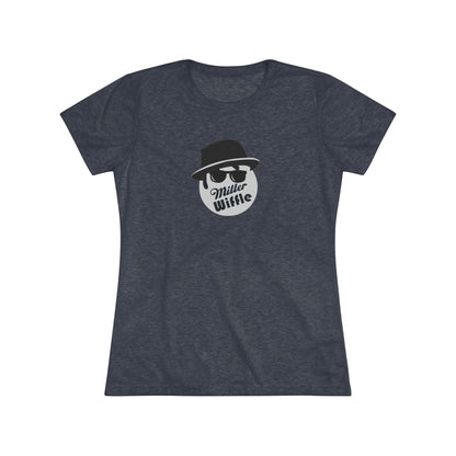 A cozy red t-shirt, the Miller Wiffel Ball - Blues Brothers - Women's Triblend Tee by Printify, features a graphic of a masked face wearing a fedora hat and sunglasses, along with the text "Miller Wiffle." The t-shirt is displayed on a wooden floor, paired with a denim jacket, white sneakers, and a potted green plant to create a vintage look.