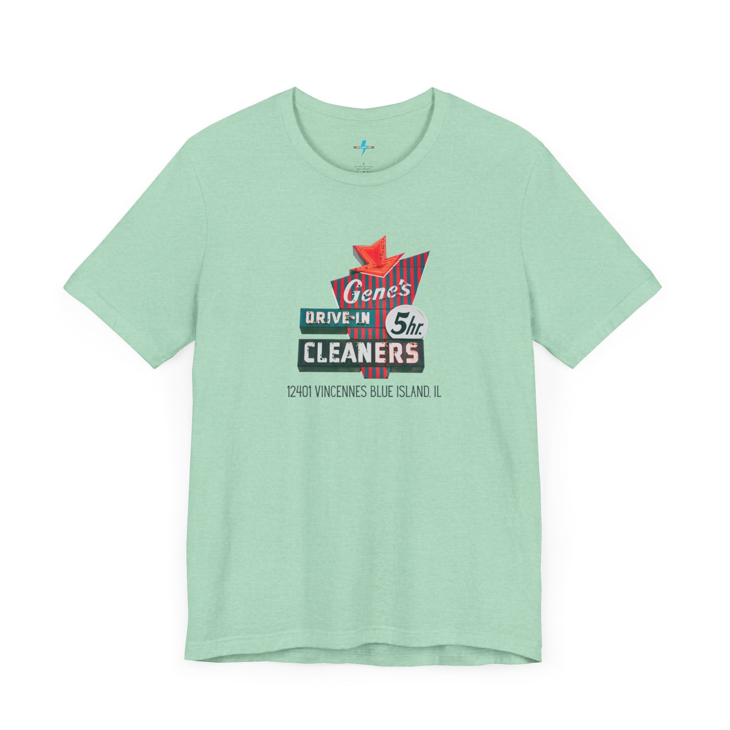 A unisex Jersey short sleeve tee from Printify featuring a light grey color with a retro-style graphic in the center. The design showcases text that reads "Gene's Drive In Cleaners, 5th," along with the address "12401 Vincennes Blue Island IL" in a blend of vintage fonts and colors, evoking the classic Chicago Fire-era vintage sign aesthetic.