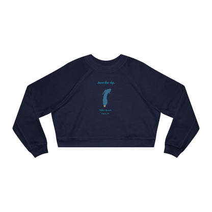 The "Just the Tip - Miller Beach" Women's Cropped Fleece Pullover by Printify is a beige sweatshirt with long sleeves and a crew neck. It features a blue-green abstract feather design in the center with the words "Just the tip" above it, and "Silly Peach" along with "Gary, IN." below. This pullover is crafted from premium tri-blend fabric for ultimate comfort and style.