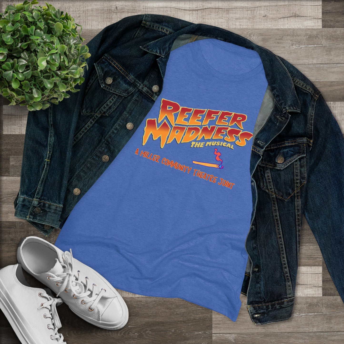 This limited-edition dark gray "Reefer Madness Cast Shirt - Miller Community Theatre - Women's Triblend Tee" by Printify features the text "Reefer Madness: The Musical" in bold, fiery letters across the chest. Below, in smaller orange text, it reads, "A Hill's Community Theatre Joint.