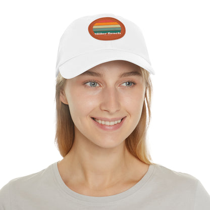 The Miller Beach Retro Sunset - Dad Hat with Leather Patch (Round) by Printify is a pink baseball cap crafted from bio-washed chino twill for added comfort. It features a PU leather patch adorned with horizontal stripes in red, orange, yellow, green, and blue. Below the stripes, "Miller Beach" is embroidered in white. An adjustable strap at the back ensures a perfect fit.