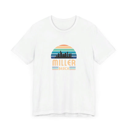 The Printify Miller Beach Chicago Skyline - Unisex Jersey Short Sleeve Tee is a light blue T-shirt featuring a stylized graphic of the Chicago skyline against a setting sun with gradient shades of blue and orange. Below the graphic, "Miller Beach" is printed in bold, yellow letters.