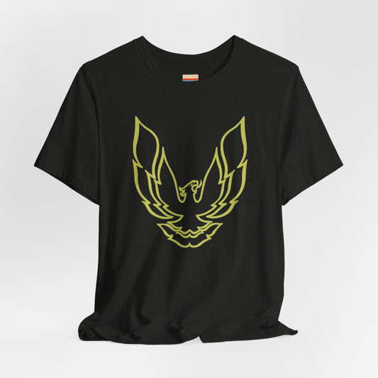 The Pontiac Trans Am Phoenix Shirt - Unisex Jersey Short Sleeve Tee by Printify is a classic black T-shirt that showcases a stylized yellow phoenix design on the front, reminiscent of the iconic Pontiac Trans Am. The shirt is displayed laid flat against a white background.