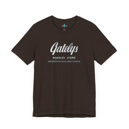 A green unisex jersey short sleeve tee from Printify's SoCool Shirts collection, featuring "Gately's People's Store" printed prominently in white on the front. Below this, smaller text reads "Tinley Park's Brementowne Mall" in white. The T-shirt is displayed against a plain white background and is named the "Gatelys Peoples Store - Vintage 1980s.