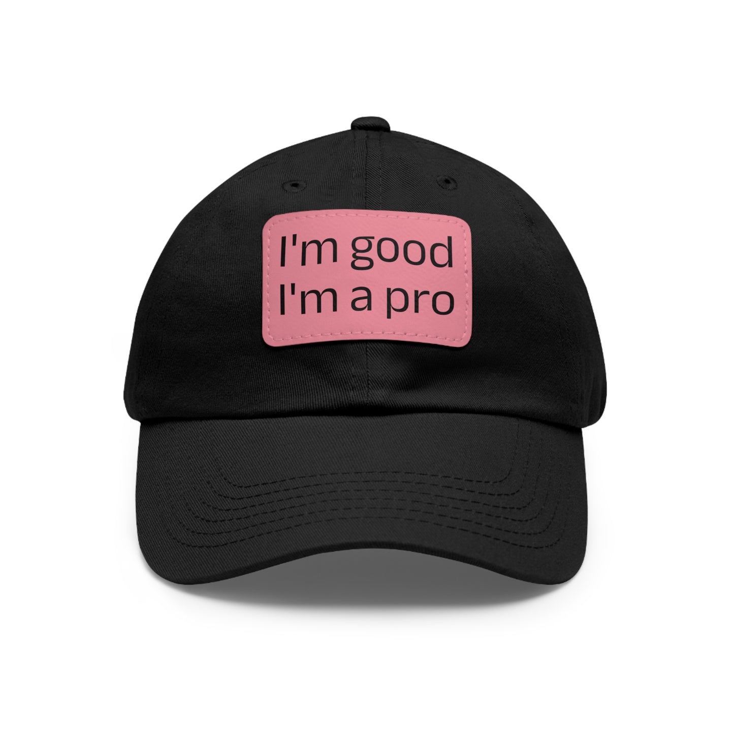 The Printify Dad Hat with Leather Patch (Rectangle) is a black, six-panel low-profile baseball cap made from bio-washed chino twill. This personalized Dad hat features a curved brim, visible stitching details, and a rectangular leather patch on the front that reads "I'm good I'm a pro" in grey text.