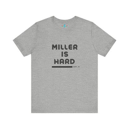 A unisex jersey short sleeve tee from Printify in burnt orange features the bold black text "MILLER IS HARD" on the chest, with "GARY, IN" written beneath in smaller black font. Perfect for showcasing Miller Beach's iconic spirit, this t-shirt is displayed against a plain white background.