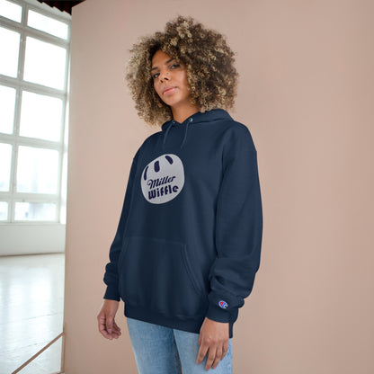 A navy blue Printify Miller Beach Wiffle Ball OG Logo - Sweatshirt, featuring a white wiffle ball graphic on the chest with "Miller Wiffle" in blue beneath it. Made from recycled polyester, this hoodie includes a front pocket, drawstrings, and the Champion logo on the left sleeve. It also offers Double Dry® technology for added comfort.