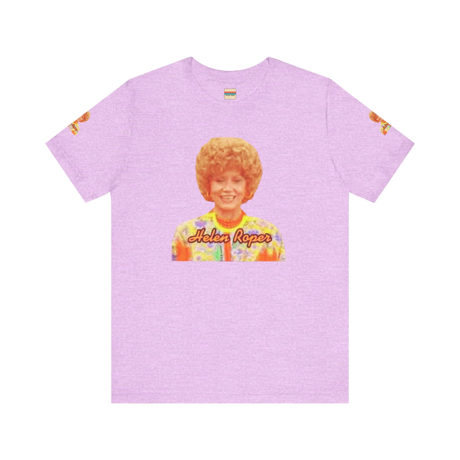 A lavender-colored Helen (Mrs.) Roper Three's Company - Unisex Jersey Short Sleeve Tee by Printify is hanging on a wooden hanger against a white background. This T-shirt features an image of a smiling person with curly hair wearing a colorful blouse, with the text "Helen Roper" underneath the image. Both sleeves have identical designs, making it perfect Three's Company merchandise.