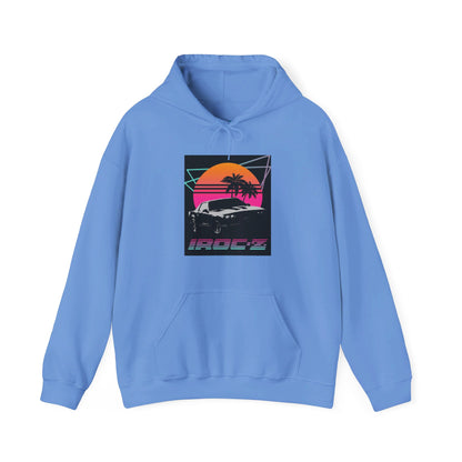 Introducing the Chevrolet IRoc Z28 - 1980s Retro Hoodie by Printify: This vibrant pink hoodie showcases a striking retro design on the front, featuring a classic American muscle car set against an orange and red sunset with palm trees, intersected by geometric shapes. The text "IROCZ" is prominently displayed below the image. Offering a relaxed fit and equipped with a front pocket, this hoodie perfectly captures the essence of 1980s style.