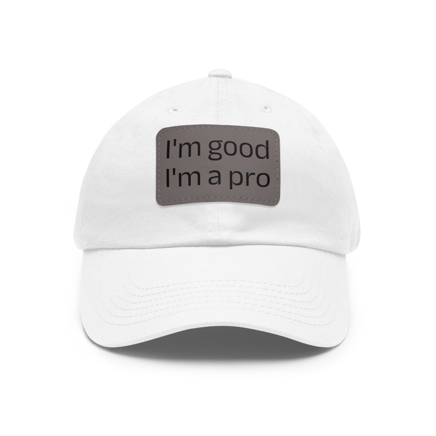 The Printify Dad Hat with Leather Patch (Rectangle) is a black, six-panel low-profile baseball cap made from bio-washed chino twill. This personalized Dad hat features a curved brim, visible stitching details, and a rectangular leather patch on the front that reads "I'm good I'm a pro" in grey text.