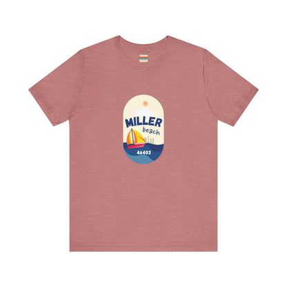 The Miller Beach Sailboat - Unisex Jersey Short Sleeve Tee by Printify features a vibrant graphic design portraying a sailboat on water with a sun above it and the text "MILLER beach 46403." This white retail fit shirt is crafted from soft Airlume combed cotton and showcases rounded graphics in blue, orange, and yellow.