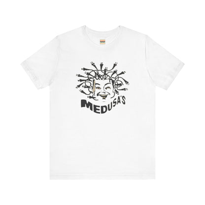 A cream-colored unisex jersey short sleeve tee from Printify, titled "Medusa's 1980s Dance Club Chicago," features a black and white illustration of a cartoonish Medusa head. The soft cotton design showcases numerous snakes as hair with a smiling face. Below, the word "MEDUSA'S" is printed in bold, playful font.