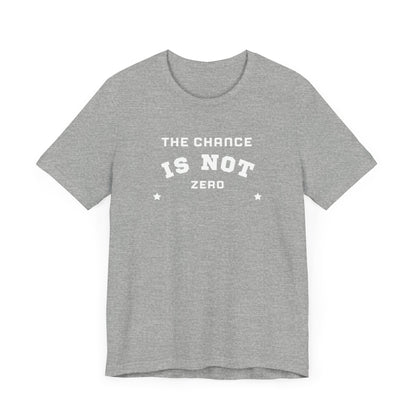 Folded light red Unisex Jersey Short Sleeve Tee from Printify, featuring bold white text that reads "THE CHANCE IS NOT ZERO" along with two star illustrations. This motivational T-shirt, made from breathable fabric, is neatly stacked with another identical shirt underneath.