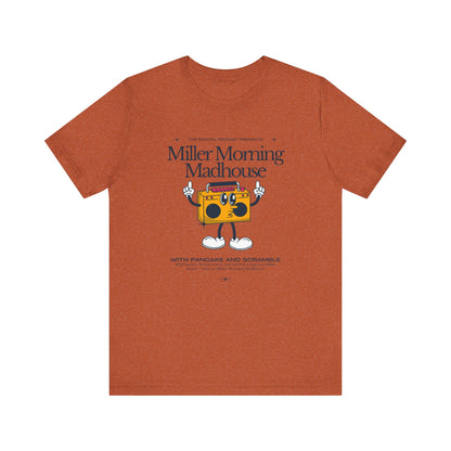 This Printify unisex jersey short sleeve tee in Sand Dune features a playful boombox cartoon character with arms, legs, and sunglasses. Emblazoned with "Miller Morning Madhouse," it highlights podcast details from "The School Podcast Presents.