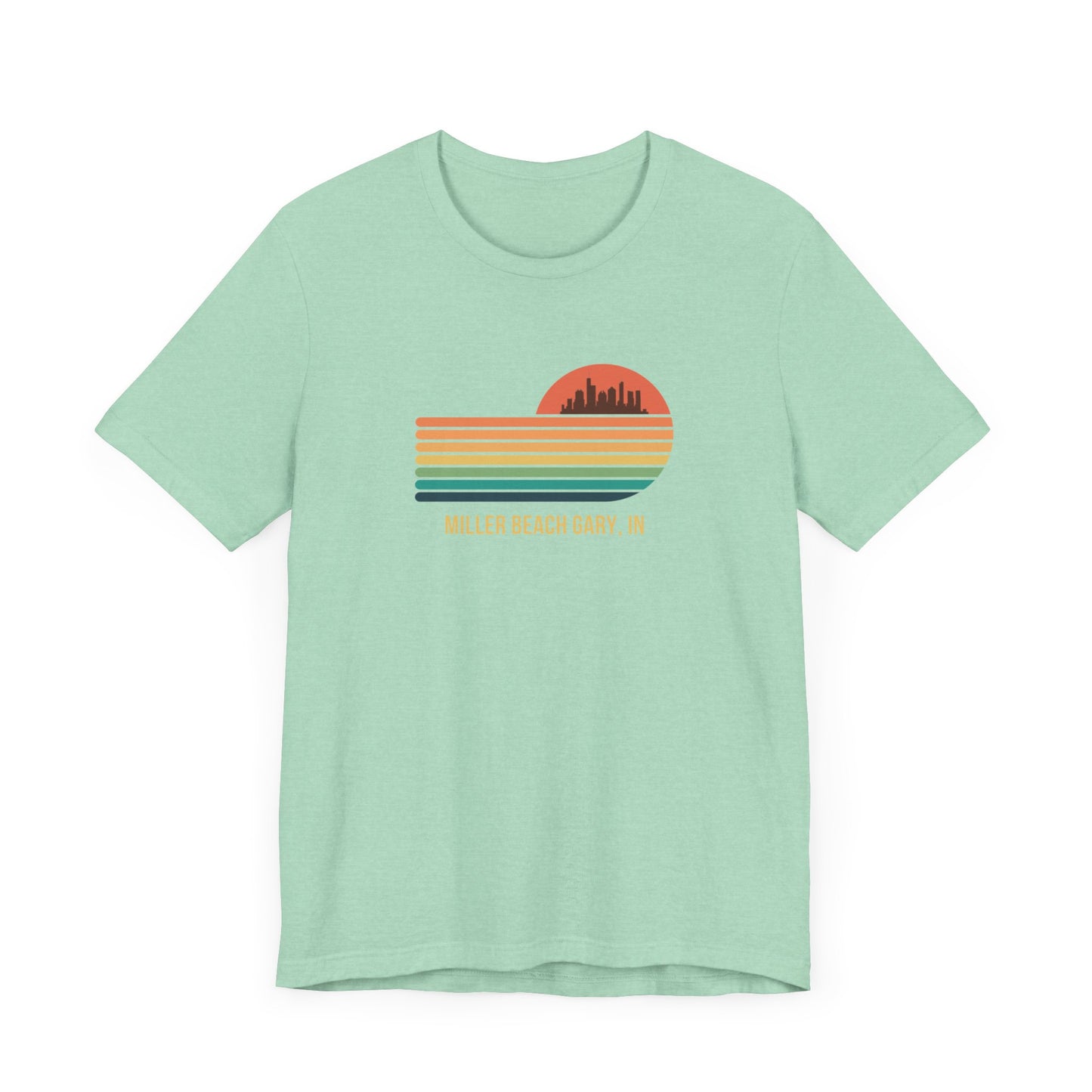 Introducing the Miller Beach Gary, IN Sunset Gradient - Unisex Jersey Short Sleeve Tee by Printify. This stylish blue T-shirt features a circular sunset graphic on the chest, showcasing a black city skyline silhouette against an orange-red sunset with horizontal stripes in green, yellow, and orange. Below the graphic reads "MILLER BEACH GARY, IN." Crafted from soft cotton for extra beachy charm.