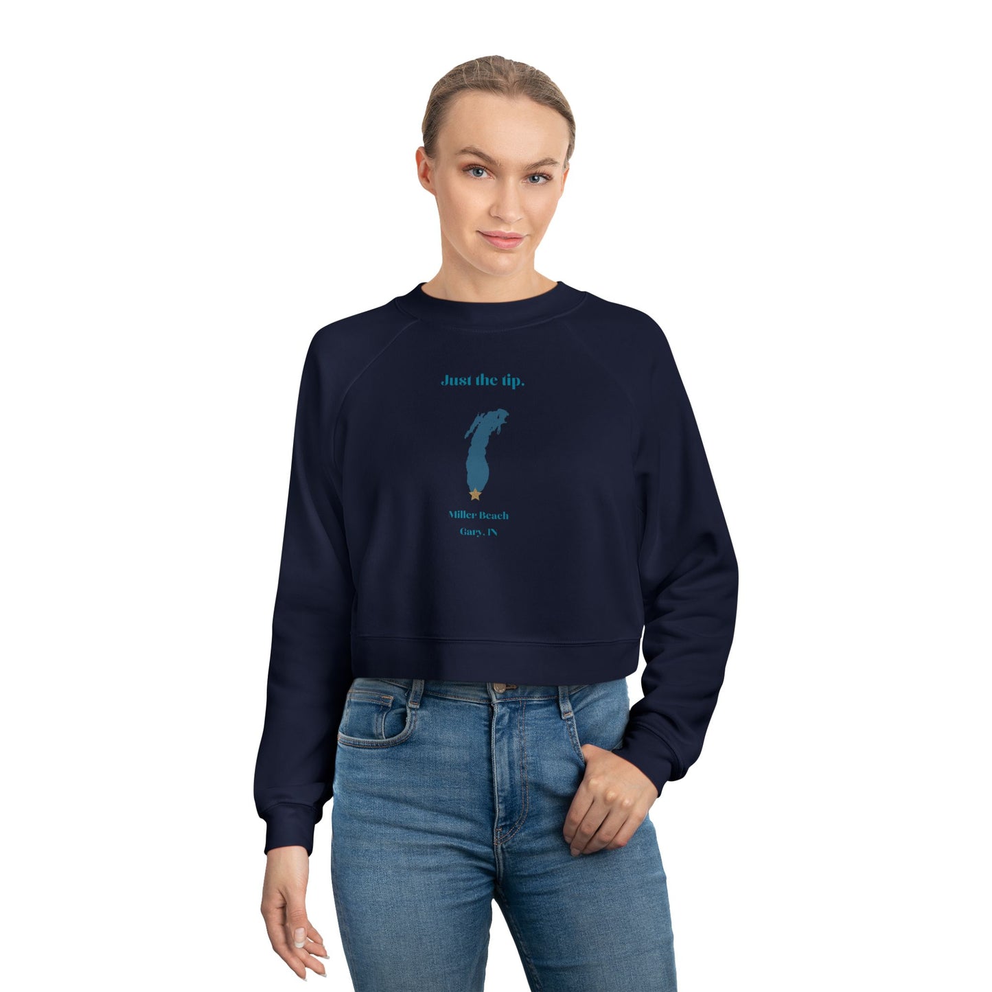 The "Just the Tip - Miller Beach" Women's Cropped Fleece Pullover by Printify is a beige sweatshirt with long sleeves and a crew neck. It features a blue-green abstract feather design in the center with the words "Just the tip" above it, and "Silly Peach" along with "Gary, IN." below. This pullover is crafted from premium tri-blend fabric for ultimate comfort and style.