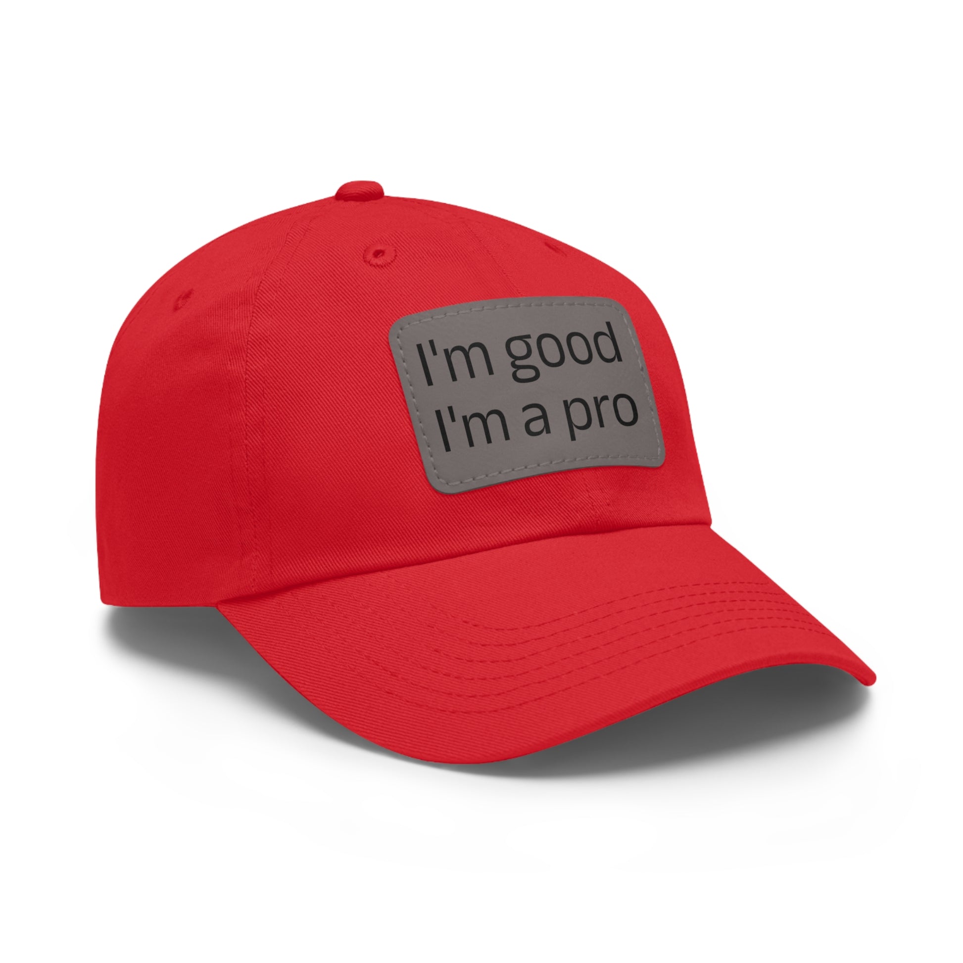 The Printify Dad Hat with Leather Patch (Rectangle) is a black, six-panel low-profile baseball cap made from bio-washed chino twill. This personalized Dad hat features a curved brim, visible stitching details, and a rectangular leather patch on the front that reads "I'm good I'm a pro" in grey text.