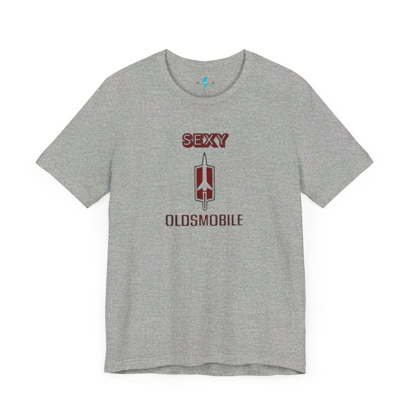 Introducing the Sexy Oldsmobile - Unisex Jersey Short Sleeve Tee by Printify, a light gray t-shirt featuring a striking graphic in the center. The design includes the word "SEXY" in bold red letters above a vertical Oldsmobile logo, underlined by the word "OLDSMOBILE" in red letters. This t-shirt is perfect for vintage car enthusiasts and comedy lovers alike, with its plain white background accentuating the bold design.