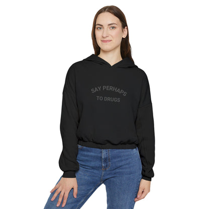 A person confidently stands in front of the camera with one hand on their hip, wearing a Printify "Say Perhaps to Drugs" Women's Cinched Bottom Hoodie. Crafted from soft Airlume cotton, this light-colored cropped hoodie pairs stylishly with blue jeans.