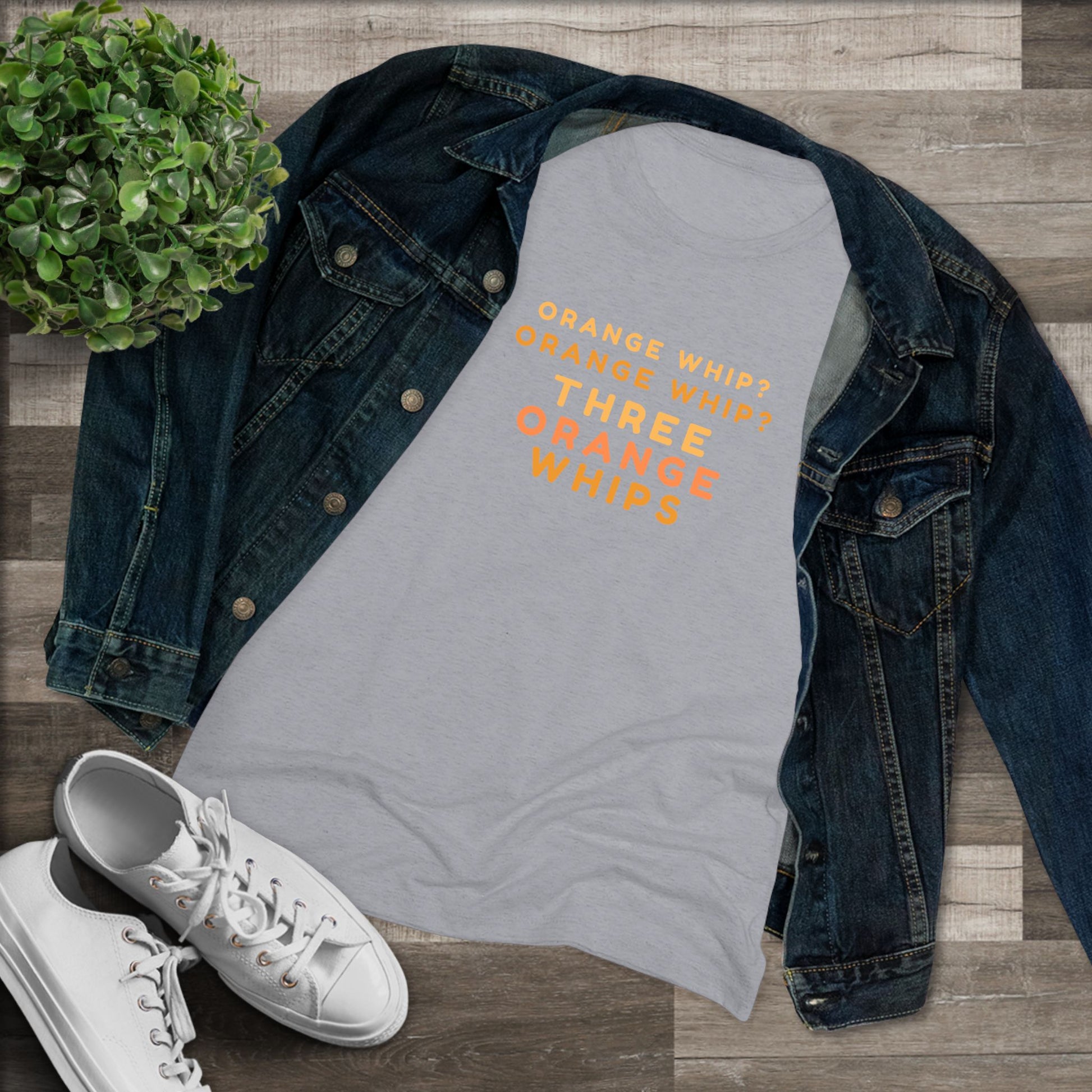 This Blues Brothers women's triblend tee from Printify features a dark gray vintage look with the text "ORANGE WHIP? ORANGE WHIP? THREE ORANGE WHIPS" printed in bright orange and yellow in the center. With a round neck and short sleeves, it's perfect for that retro vibe.