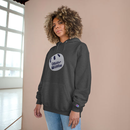 A navy blue Printify Miller Beach Wiffle Ball OG Logo - Sweatshirt, featuring a white wiffle ball graphic on the chest with "Miller Wiffle" in blue beneath it. Made from recycled polyester, this hoodie includes a front pocket, drawstrings, and the Champion logo on the left sleeve. It also offers Double Dry® technology for added comfort.