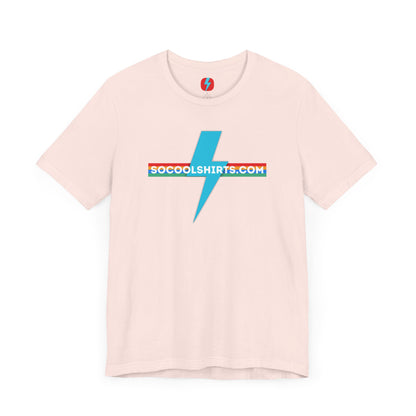 This unisex jersey short sleeve tee by Printify features a striking maroon color with a central light blue lightning bolt design. The text "SOCOOLSHIRTS.COM" is prominently displayed across the lightning bolt in white letters, set against a multicolored background that exudes retro vibes. The shirt is shown laid flat on a white backdrop.