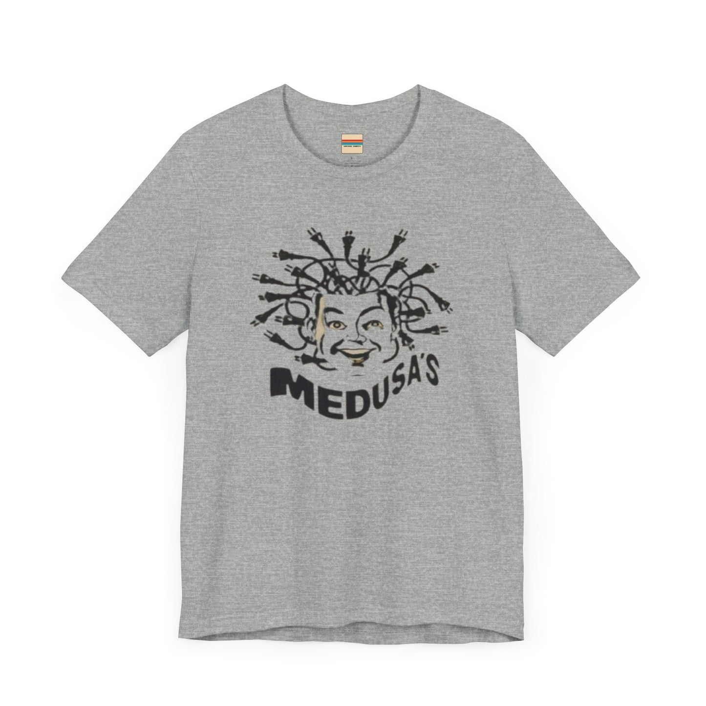 A cream-colored unisex jersey short sleeve tee from Printify, titled "Medusa's 1980s Dance Club Chicago," features a black and white illustration of a cartoonish Medusa head. The soft cotton design showcases numerous snakes as hair with a smiling face. Below, the word "MEDUSA'S" is printed in bold, playful font.