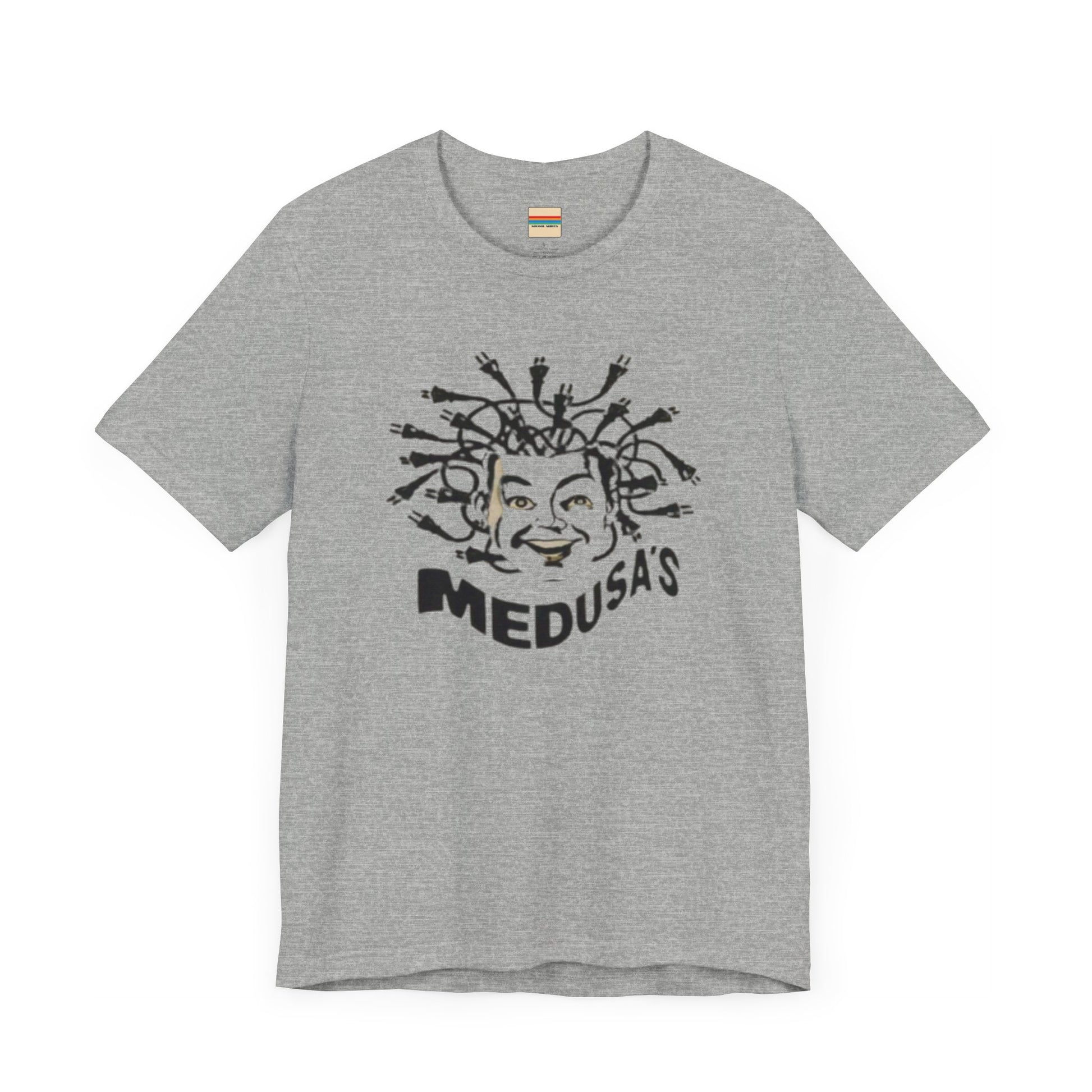 A cream-colored unisex jersey short sleeve tee from Printify, titled "Medusa's 1980s Dance Club Chicago," features a black and white illustration of a cartoonish Medusa head. The soft cotton design showcases numerous snakes as hair with a smiling face. Below, the word "MEDUSA'S" is printed in bold, playful font.