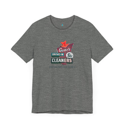 A unisex Jersey short sleeve tee from Printify featuring a light grey color with a retro-style graphic in the center. The design showcases text that reads "Gene's Drive In Cleaners, 5th," along with the address "12401 Vincennes Blue Island IL" in a blend of vintage fonts and colors, evoking the classic Chicago Fire-era vintage sign aesthetic.