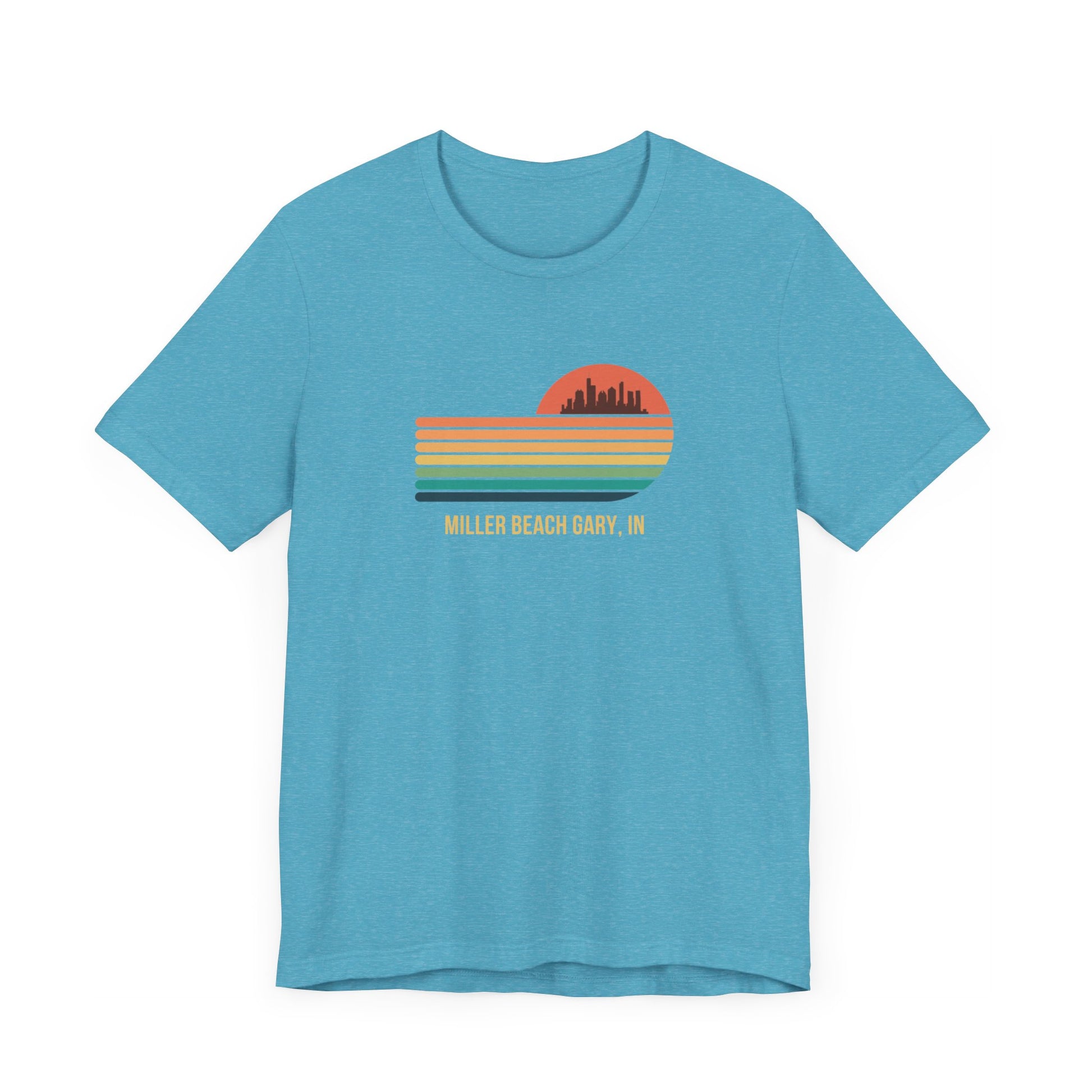 Introducing the Miller Beach Gary, IN Sunset Gradient - Unisex Jersey Short Sleeve Tee by Printify. This stylish blue T-shirt features a circular sunset graphic on the chest, showcasing a black city skyline silhouette against an orange-red sunset with horizontal stripes in green, yellow, and orange. Below the graphic reads "MILLER BEACH GARY, IN." Crafted from soft cotton for extra beachy charm.