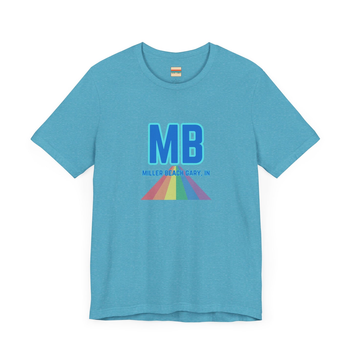 The Miller Beach Pride - Unisex Jersey Short Sleeve Tee by Printify is a white shirt made from 100% Airlume combed cotton. It showcases a design with large, bold blue letters "MB" at the top. Beneath it, the text "MILLER BEACH GARY, IN" is written in blue. A colorful, triangular rainbow graphic extends downward from the text, symbolizing Miller Beach pride.