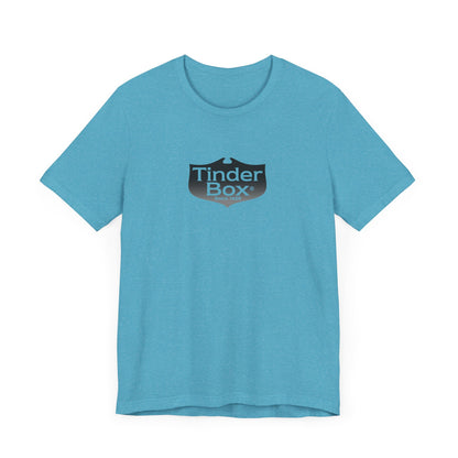 A light blue Printify "The Tinder Box 1980s" unisex jersey short sleeve tee featuring the "Tinder Box" logo in the center. The logo consists of a dark shield with the words "Tinder Box" in white text, with a small flame icon replacing the dot above the "i".