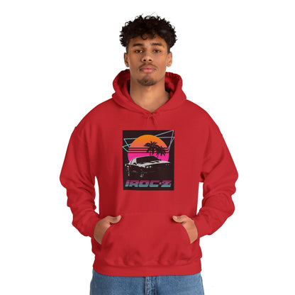 Introducing the Chevrolet IRoc Z28 - 1980s Retro Hoodie by Printify: This vibrant pink hoodie showcases a striking retro design on the front, featuring a classic American muscle car set against an orange and red sunset with palm trees, intersected by geometric shapes. The text "IROCZ" is prominently displayed below the image. Offering a relaxed fit and equipped with a front pocket, this hoodie perfectly captures the essence of 1980s style.