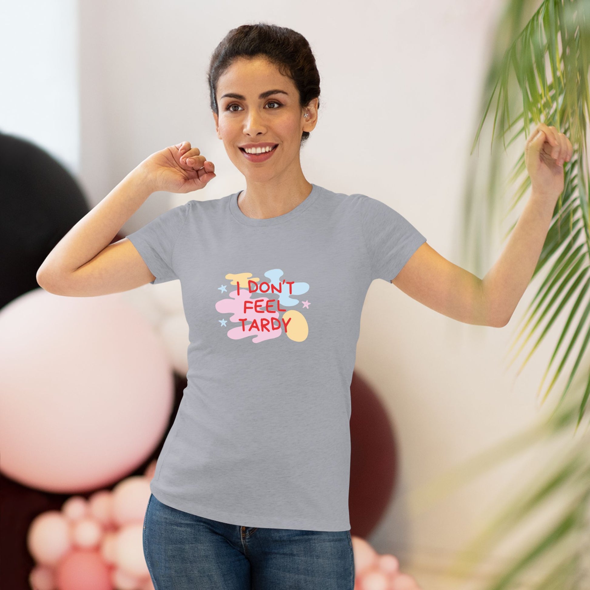 A light gray, short-sleeved Women's Triblend Tee from Printify with the playful phrase "I DON'T FEEL TARDY" printed in colorful letters on the front. The text is surrounded by abstract pastel shapes, giving it retro vibes and a vintage look reminiscent of a Van Halen T-shirt.