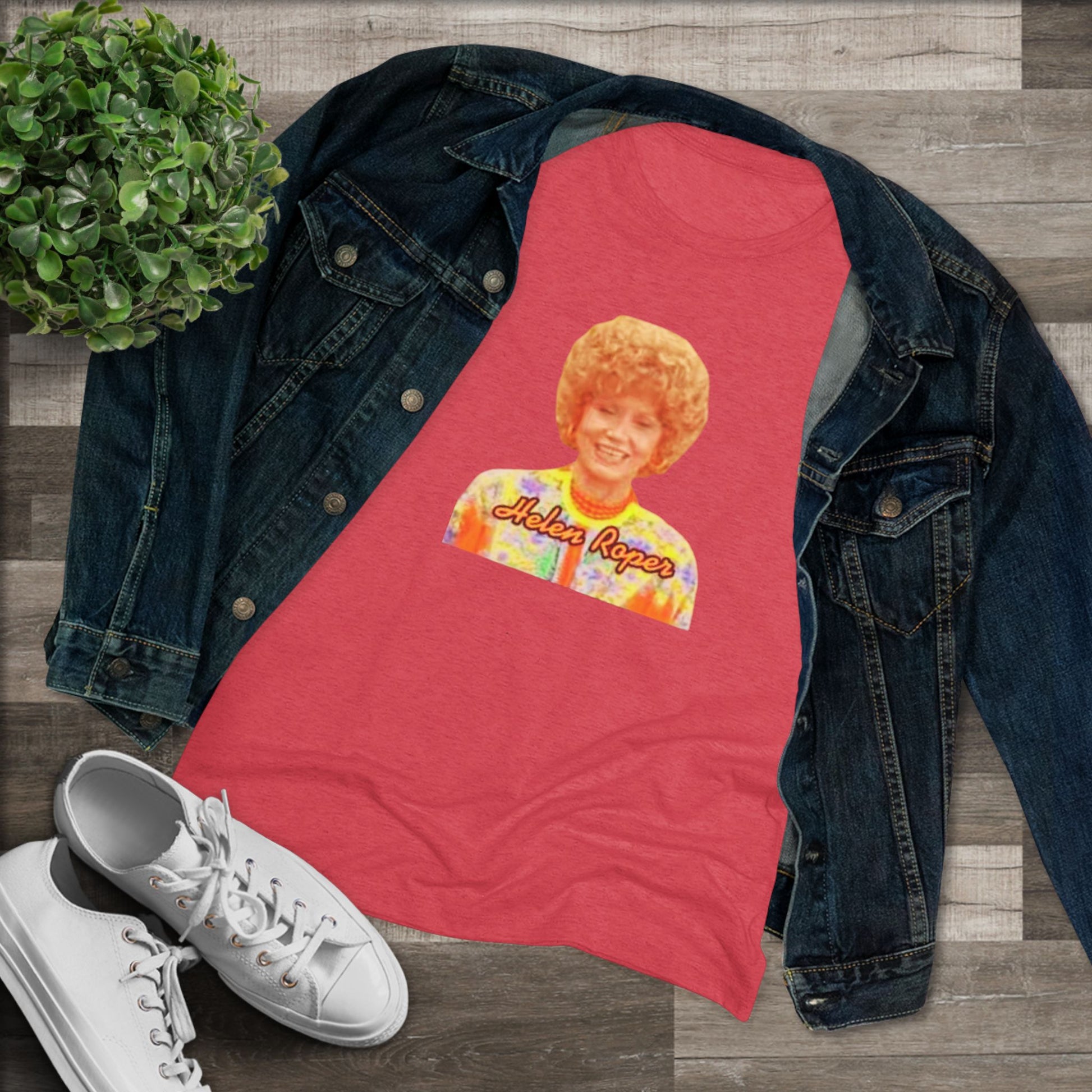 A Women's Triblend Tee by Printify, titled "Helen Roper - Three's Company," features a red design with an illustration of a smiling person with curly hair and colorful clothing. Below the illustration, the text "Helen Roper" is written in a bold, retro font, capturing the essence of vintage TV humor.